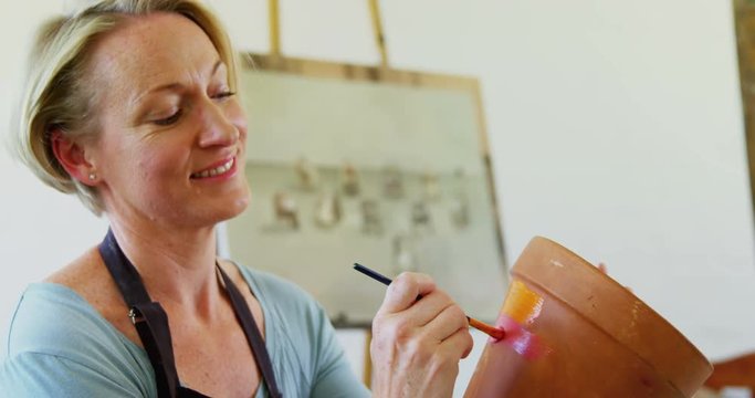 Woman painting pot in drawing class 
