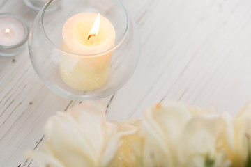 Fototapeta na wymiar Big palm candle in glass ball with white roses