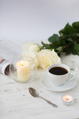 Coffee for breakfast or lunch with decorations, candles and flowers. white roses on the table and cup of coffee