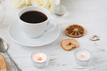 Coffee for breakfast or lunch with decorations, candles and flowers. white roses on the table and cup of coffee