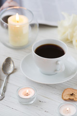 Coffee for breakfast or lunch with decorations, candles and flowers. white roses on the table and cup of coffee