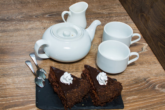 a teapot and a couple of cups with a cake on the table