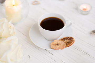 Coffee for breakfast or lunch with decorations, candles and flowers. white roses on the table and cup of coffee