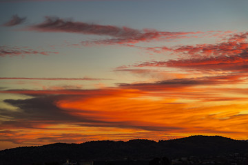 super orange clouds during sunset over a small mountain range