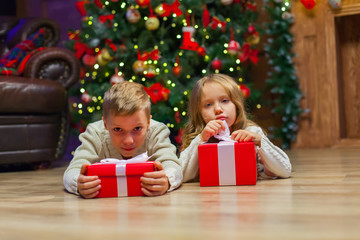 Fototapeta na wymiar children lie near Christmas Present In Front Of Tree
