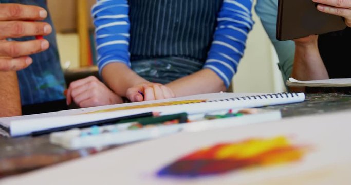 Mid section of artist interacting with each other at table 