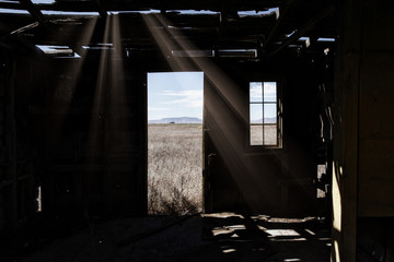 Wood frame room, abandoned and disintegrating, sunlight shining through cracks