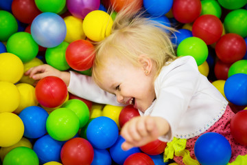 THE BABY IS PLAYING IN COLORED BALLS