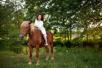 Beautiful woman is riding a horse. Summer meadow.