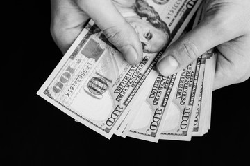 The white young man counts the money, one hundred new dollar bills on a black background close plan. Concepts of business and finance. top view .