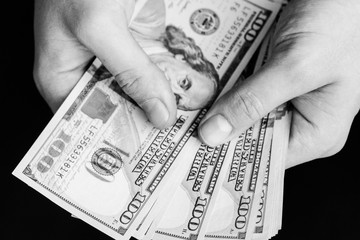 The white young man counts the money, one hundred new dollar bills on a black background close plan. Concepts of business and finance. top view .