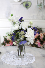 the Bouquet of artificial roses, phlox and bells on a table in a vase, as an interior decoration