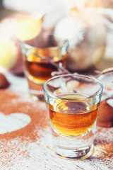 Whiskey or liqueur, truffle chocolate candies in cocoa powder and christmas decorations on white wooden background.