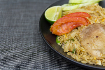 Fried rice with pork, lime, potato and cucumbers in black plate
