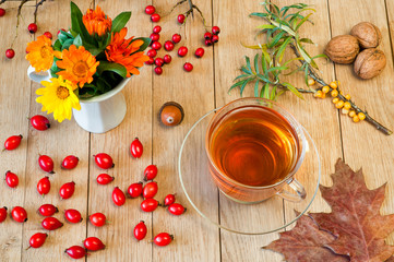 Black herbal tea in a transparent cup on a wooden table. Autumn concep