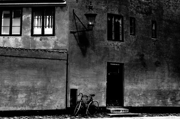 Black and white photo. Old house in Copenhagen, texture wall and bicycle near the door.