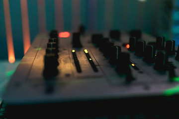 DJ control panel close-up. Blurred DJ mixer. Warm light. Background for a DJ's