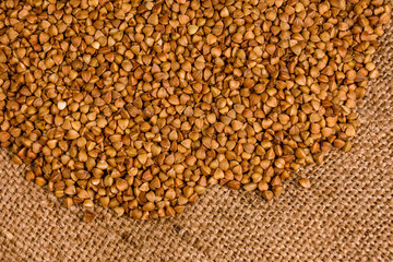 Pile of the raw buckwheat on sackcloth. Top view
