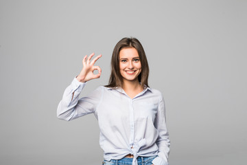 Portrait of cheerful smiling woman showing okay gesture, with copyspace, over grey background