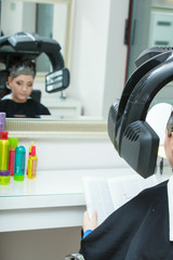 Woman in hairdresser, drying hair under machine
