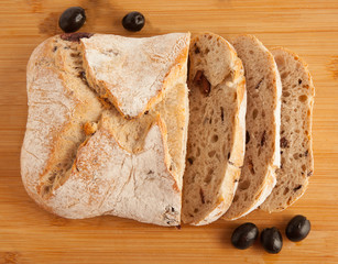 Bread, ciabata with dried tomatoes and olives, on a board, isolated on white background
