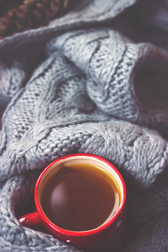 Winter background - hot tea in red cup and gray woolen scarf