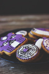 Royal icing cookies-plate with decorated purple cookies in different shapes and decoration; on wooden table