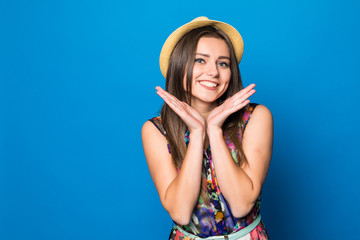 Naklejka premium Portrait of a happy excited young woman in beach hat with smile looking at camera isolated over blue background