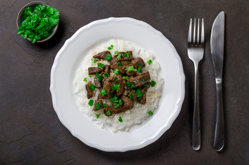 Cooked rice and fried beef with parsley served in white plate on