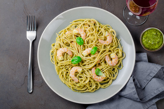 Spaghetti with fried prawns and pesto sauce in a gray plate, red