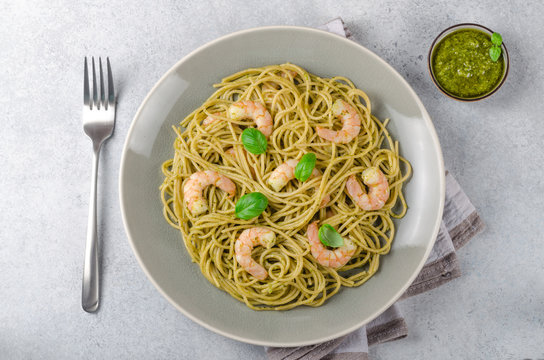 Spaghetti with fried prawns and pesto sauce in a gray plate, sto
