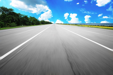 Fototapeta premium An empty countryside road with motion blur against a blue sky with clouds