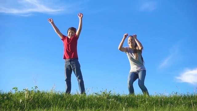 Happy family jumping on green grass hill at blue sky