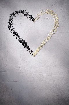 Heart made with black and white sesame seeds, on gray background. Love, Valentine's day concept. Top view, copy space.