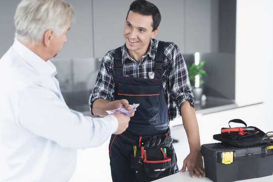 A plumber man communicates with a client who pays for the work done. The old man gives the plumber a fee.