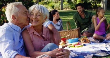 Affectionate senior couple sitting in park  - Powered by Adobe