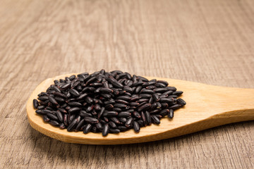 Black Rice seed. Grains in wooden spoon. Rustic.