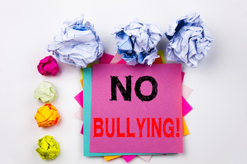 Writing text showing No Bullying written on sticky note in office with screw paper balls. Business concept for Bullies Prevention Against School Work or Cyber Internet Harassment on the background.