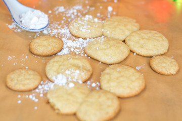 Freshly baked sugar cookies on wooden board with colored lights in background, selective focus