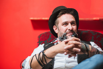 Bearded male tattoo master with tattoo machine gun in hands