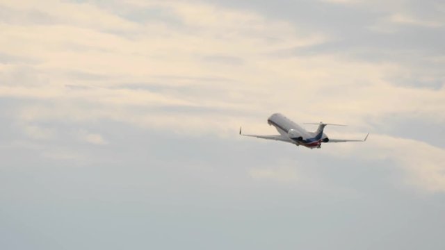 White airplane gains height in overcasted sky after taking off