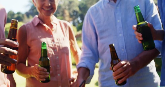 Family toasting beer while preparing barbecue in the park 