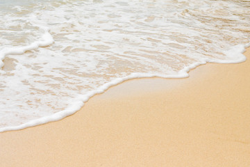 Fototapeta na wymiar White foam of waves in the coral sand