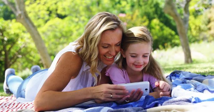 Mother and daughter taking selfie with  mobile phone in park 