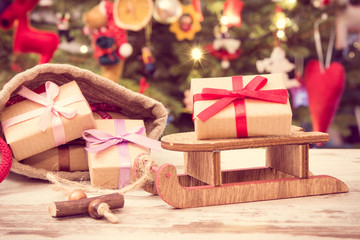 Vintage photo, Gifts for Christmas on sled and in jute bag, festive tree with decoration, Christmas time concept