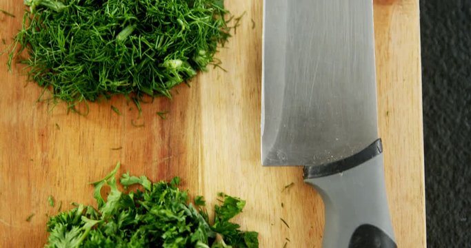 Chopped herbs with knife on chopping board 