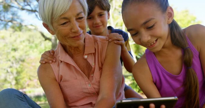 Grandmother and grand kids using mobile phone in the park 