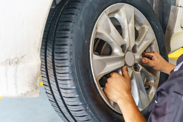 car service, repair, maintenance and people concept - auto mechanic man with electric screwdriver changing tire at workshop