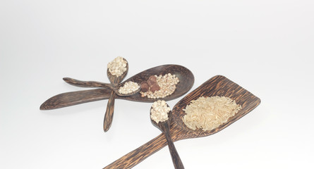 Grains in a wooden spoon on a white background.