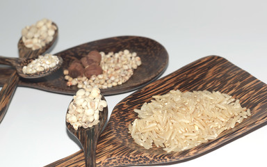 Grains in a wooden spoon on a white background.